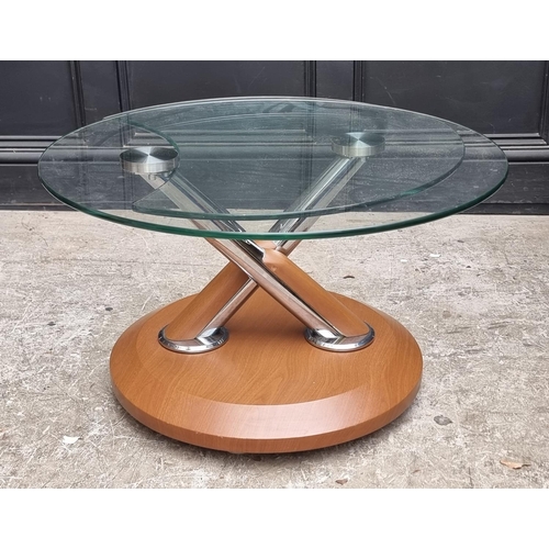 1166 - A glass swivel action coffee table, by Modesto for Magnussen, 70cm diameter when clos... 