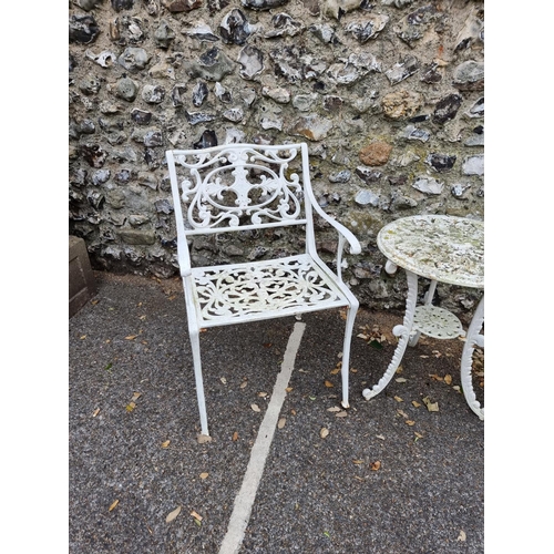 1675 - A pair of white painted cast iron garden chairs; and a similar circular table, 45cm diameter. (3)... 