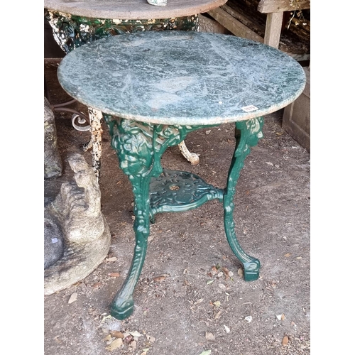 1679 - A cast iron and green marble top cafe table, 70cm high x 61cm diameter.