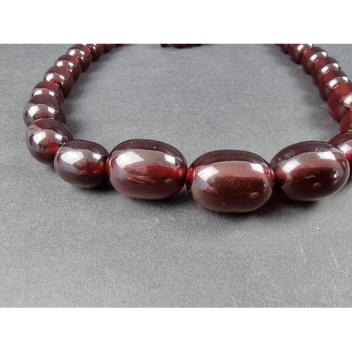 323 - A cherry amber style necklace, having thirty three beads of approximately 12-21mm diameter, 61cm lon... 