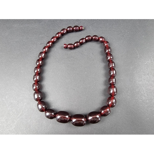 323 - A cherry amber style necklace, having thirty three beads of approximately 12-21mm diameter, 61cm lon... 