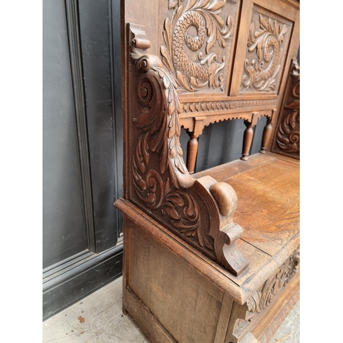 1015 - A late Victorian carved oak box seat settle, 109.5cm wide.