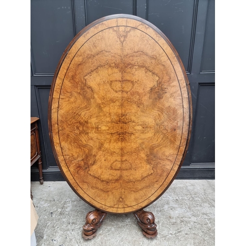 1020 - A good Victorian figured walnut oval loo table, with dolphin base, 152cm wide.