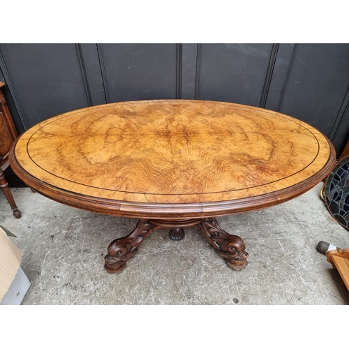 1020 - A good Victorian figured walnut oval loo table, with dolphin base, 152cm wide.