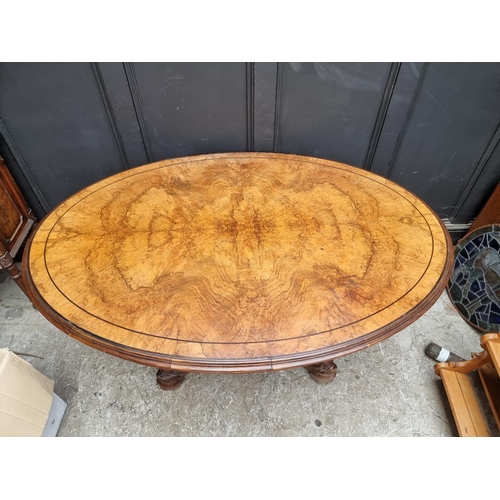 1020 - A good Victorian figured walnut oval loo table, with dolphin base, 152cm wide.