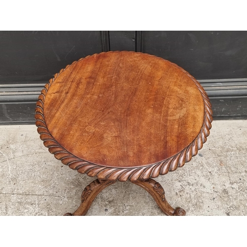 1030 - A small 19th century carved walnut low tripod table, 47cm wide. 