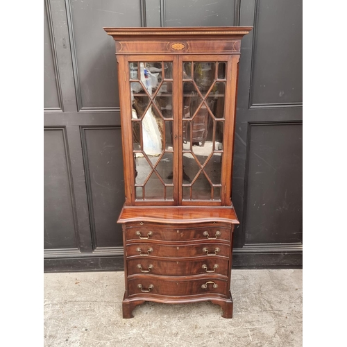 1050 - An 18th century style mahogany and inlaid bookcase, the serpentine chest base with brushing sli... 