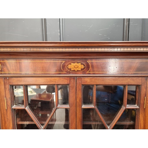 1050 - An 18th century style mahogany and inlaid bookcase, the serpentine chest base with brushing sli... 