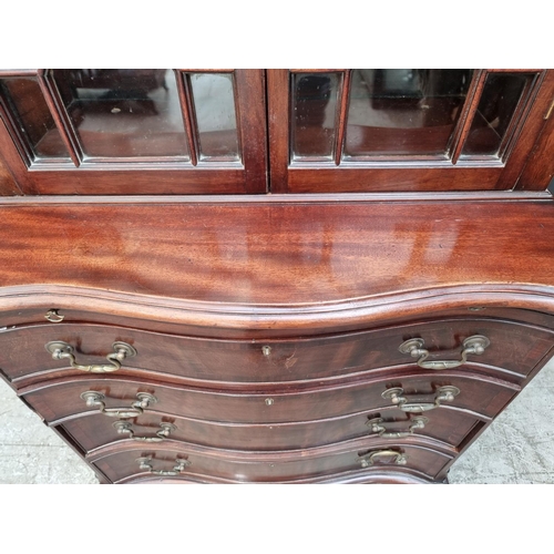 1050 - An 18th century style mahogany and inlaid bookcase, the serpentine chest base with brushing sli... 