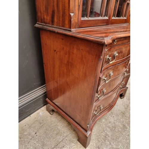 1050 - An 18th century style mahogany and inlaid bookcase, the serpentine chest base with brushing sli... 