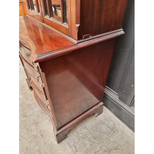 1050 - An 18th century style mahogany and inlaid bookcase, the serpentine chest base with brushing sli... 