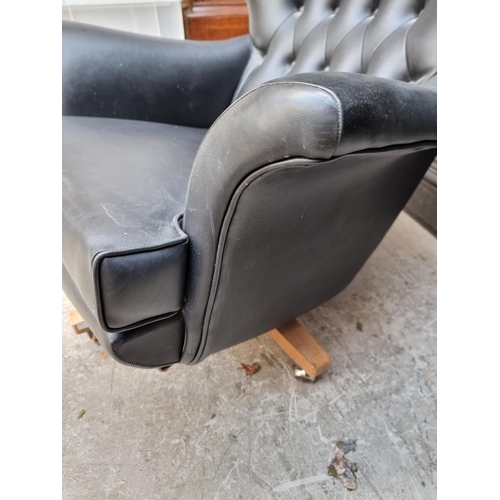 1062 - A mid-century G Plan black vinyl 'Blofeld' swivel armchair and matching stool.