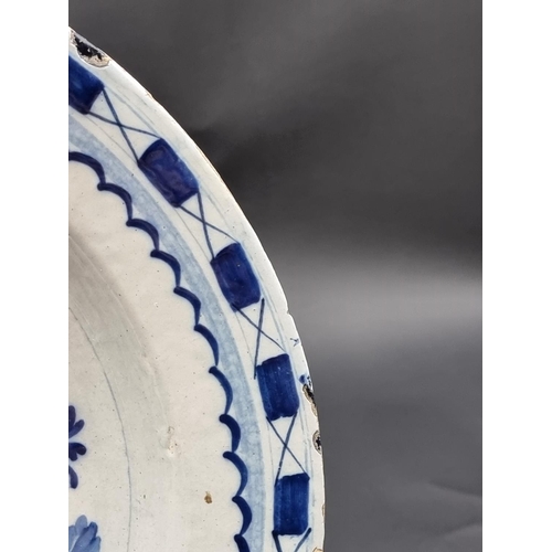 1509 - An 18th century delft blue and white charger, 35.5cm diameter, (rim chips).