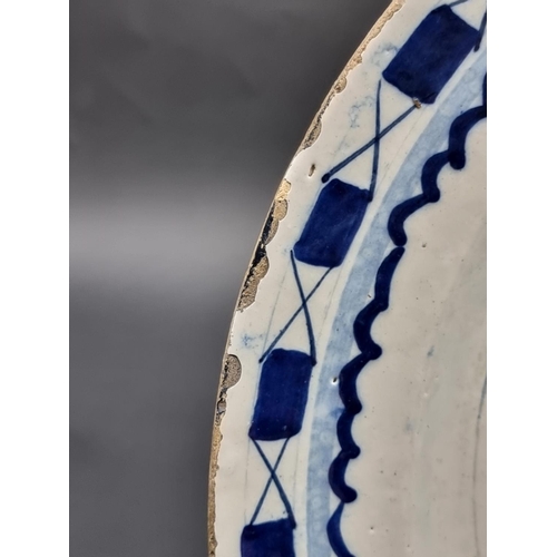 1509 - An 18th century delft blue and white charger, 35.5cm diameter, (rim chips).