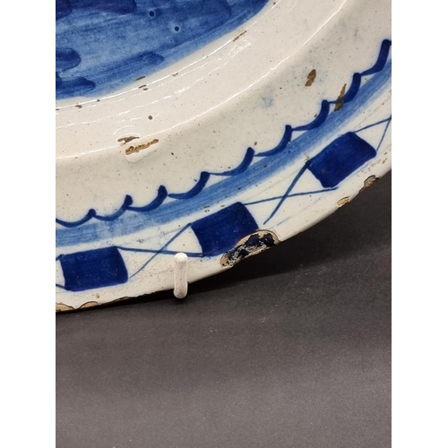 1509 - An 18th century delft blue and white charger, 35.5cm diameter, (rim chips).