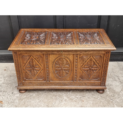 1028 - A reproduction carved oak panelled coffer, 106.5cm wide.