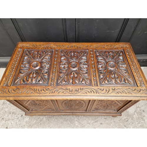 1028 - A reproduction carved oak panelled coffer, 106.5cm wide.