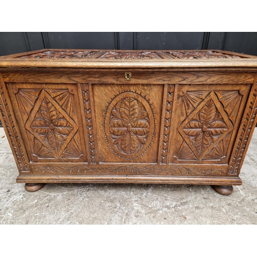 1028 - A reproduction carved oak panelled coffer, 106.5cm wide.