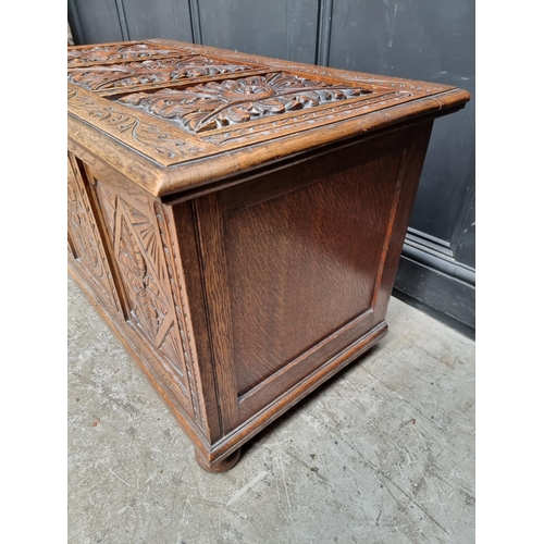 1028 - A reproduction carved oak panelled coffer, 106.5cm wide.