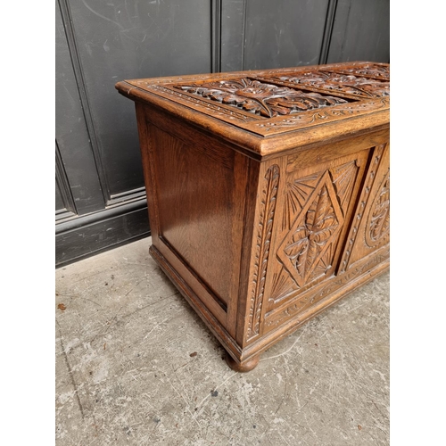 1028 - A reproduction carved oak panelled coffer, 106.5cm wide.