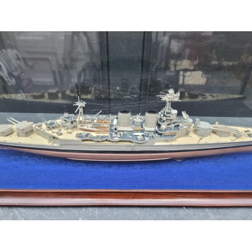 1438 - A painted model of a battleship, in glazed case, 88cm wide.