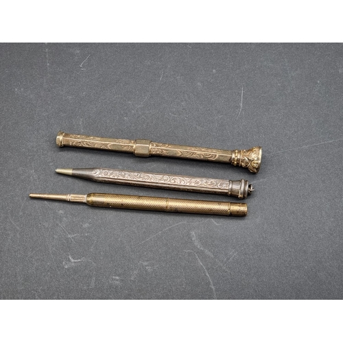 1591 - Two gilt metal propelling pencils; together with a similar white metal example. (3)