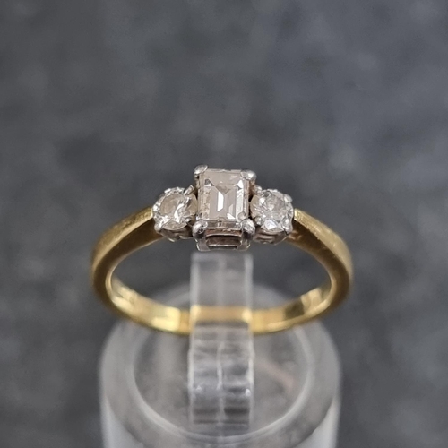 121 - An 18ct gold diamond three stone ring, set with a central trap cut diamond with a brilliant cut diam... 