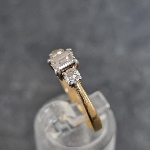 121 - An 18ct gold diamond three stone ring, set with a central trap cut diamond with a brilliant cut diam... 