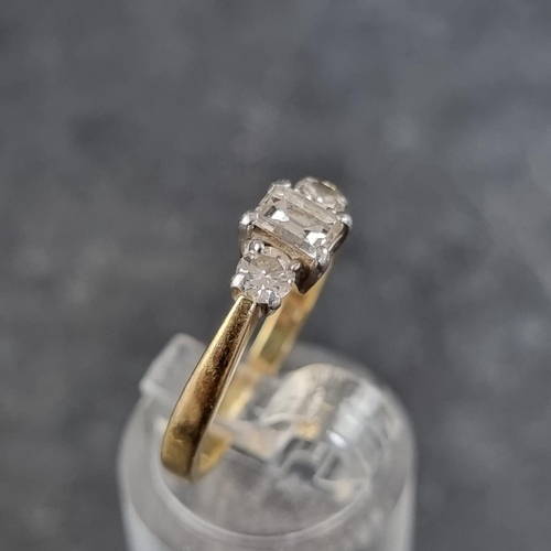 121 - An 18ct gold diamond three stone ring, set with a central trap cut diamond with a brilliant cut diam... 