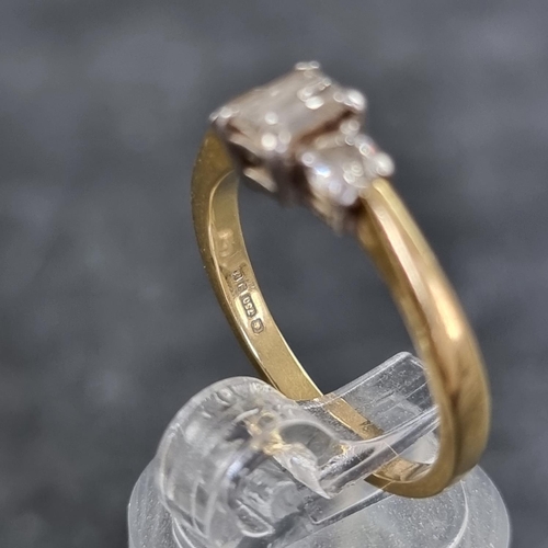 121 - An 18ct gold diamond three stone ring, set with a central trap cut diamond with a brilliant cut diam... 