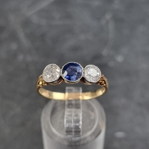 148 - A yellow metal three stone ring, set central mixed cut sapphire with an old cut diamond to each side... 