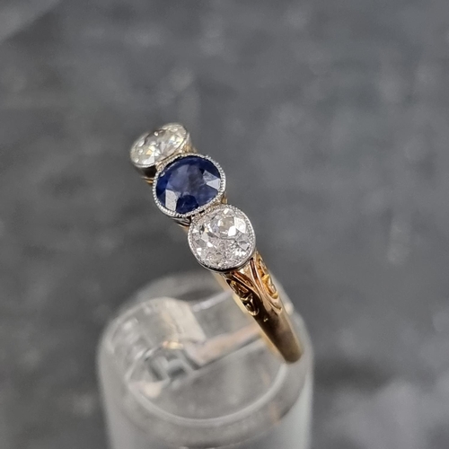 148 - A yellow metal three stone ring, set central mixed cut sapphire with an old cut diamond to each side... 