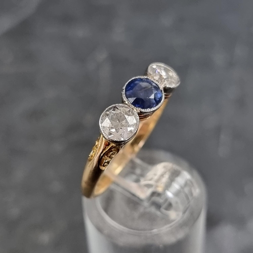 148 - A yellow metal three stone ring, set central mixed cut sapphire with an old cut diamond to each side... 