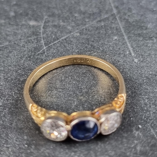 148 - A yellow metal three stone ring, set central mixed cut sapphire with an old cut diamond to each side... 