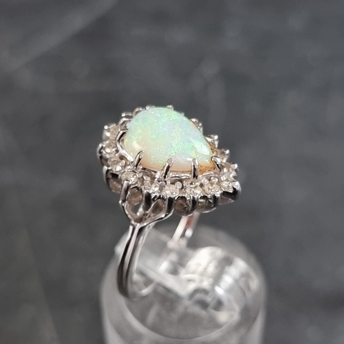 151 - An opal and diamond cluster ring, set tear drop opal surrounded by sixteen small diamonds.... 