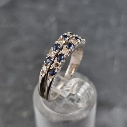 153 - A white metal ring, set two rows of interspersed sapphires and diamonds, size N.