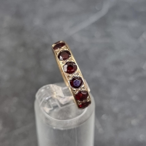 165 - A yellow metal eternity ring, set with thirteen facetted garnets, (one missing), size O.... 