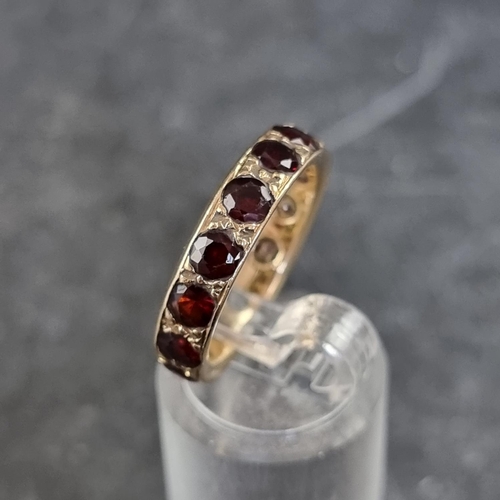 165 - A yellow metal eternity ring, set with thirteen facetted garnets, (one missing), size O.... 