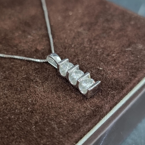 197 - A 9ct white gold pendant, set three brilliant cut diamonds, on a fine box link chain, having clasp s... 