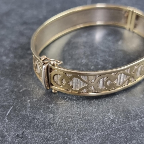 228 - A yellow metal hinged bangle, stamped 375, internal size 62 x 51mm.