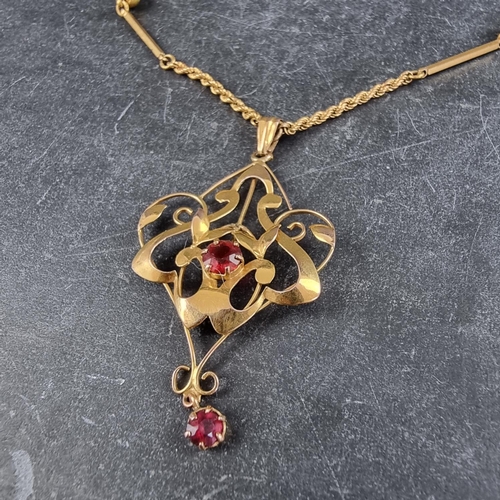 241 - An Art Nouveau style pendant, set two red gemstones, stamped '9ct', 44mm high excluding bale, on a r... 