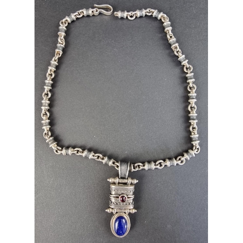 303A - A South American white metal pendant, set cabochon lapis lazuli and garnet, on a white metal tubular... 