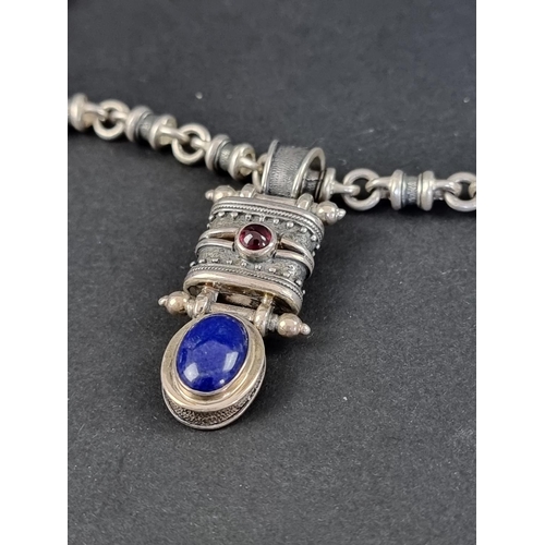 303A - A South American white metal pendant, set cabochon lapis lazuli and garnet, on a white metal tubular... 