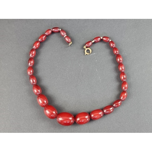 318 - A vintage cherry amber style graduated bead necklace, 38cm long, having twenty-eight beads, the larg... 