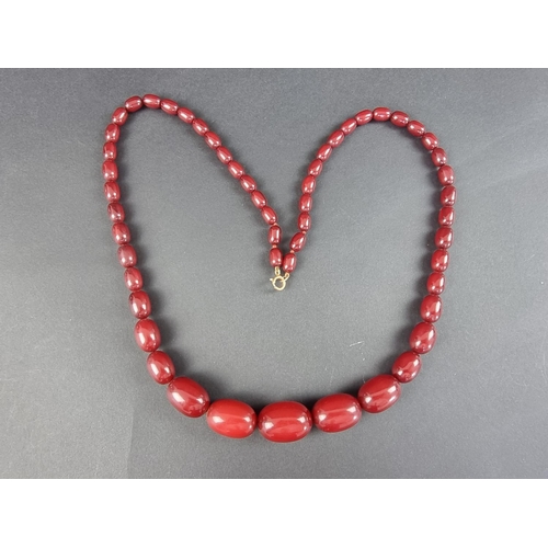 319 - A vintage cherry amber graduated necklace, having fifty-four beads, 80cm long, the largest measuring... 