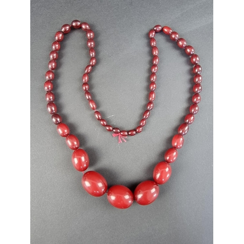 320 - A vintage cherry amber graduated necklace, 76cm long, having sixty-one, the largest measuring 28mm, ... 