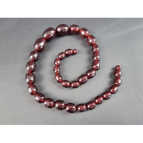 323 - A cherry amber style necklace, having thirty three beads of approximately 12-21mm diameter, 61cm lon... 