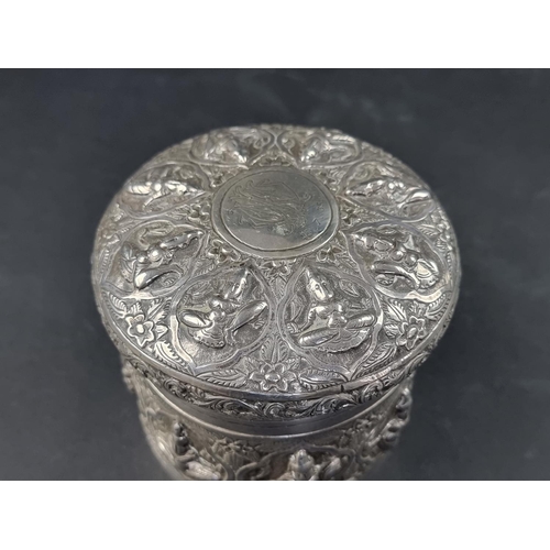 33 - An Eastern white metal cylindrical lidded box, probably Indian or Burmese, 9cm high, 11cm diameter.... 