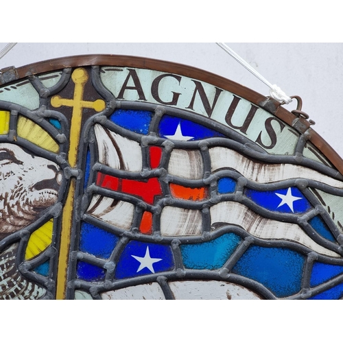 1379 - An old stained and leaded glass 'Lamb & Flag' circular panel, 54cm diameter.