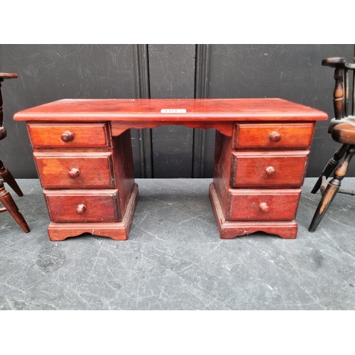 1017 - A miniature stained pine pedestal desk, 38cm wide; together with two miniature chairs, largest 38.5c... 